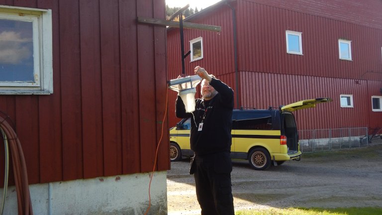 Forsker ved Veterinærinstituttet Kyrre Kausrud plasserer ut en sviknottfelle utenfor fjøs. Foto Hannah Schønhaug.